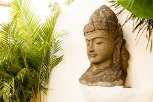 a statue of a head on a wall next to a plant at Gravity Eco Boutique Hotel - Adults Only in Uluwatu