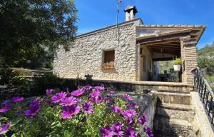 a stone house with flowers in front of it at Campus el abuelo in Denia