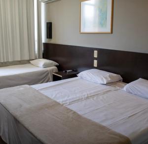 a hotel room with two beds and a picture on the wall at Coral Trade prox a Pucrs, Carlos Gomes , Araujo Vianna in Porto Alegre