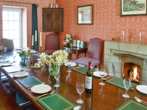 a table with a bottle of wine and a fireplace at Crogen Coach House - Oqr in Llandrillo