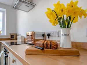 a kitchen counter with a cutting board with a toaster and yellow flowers at Gelli Villa in Llanglydwen