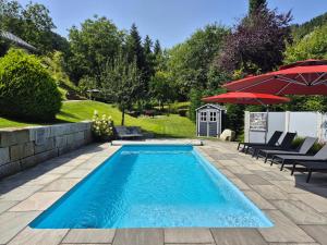 a swimming pool with a patio and an umbrella at Tiny House Eulenbach - Urlaub im Gletscherkessel Präg in Todtnau