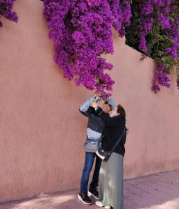two women standing next to a wall with purple flowers at As Chaves do Cantinho da Paz in Santarém