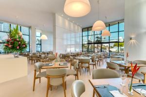 a restaurant with tables and chairs and windows at Meridiano Hotel in Maceió