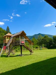un parco giochi in legno con scivolo in un campo di Cabana cu trofee a Schitu-Tarcău