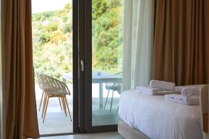 una camera con un letto e una porta a vetri con balcone di Elysium Luxury Living Skiathos a Città di Skiathos