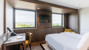アンネヴィルにあるGolden Tulip Amnéville - Hôtel Spa & Casinoのベッドと机と窓があるホテルの部屋