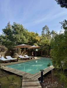a swimming pool with chairs and an umbrella at Lodge Las Luces de Algarrobo in Algarrobo