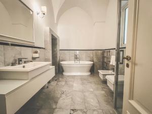 y baño con 2 lavabos, bañera y aseo. en Palazzo Epulione, en Lecce