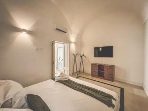 Un dormitorio con una cama y un televisor de pantalla plana. en Palazzo Epulione, en Lecce