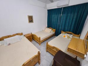 Dawwār Abū MaḩrūsにあるChalet with garden -sea view cleopatra village - kilo 86 - north coastのベッド3台と青いカーテンが備わる部屋
