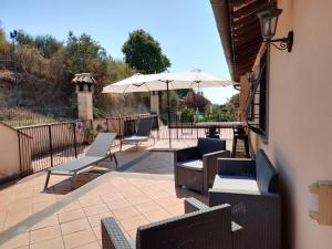 a patio with chairs and an umbrella at Attico in Villa Dona in Sacrofano