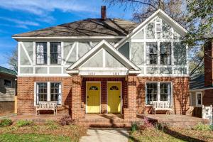 a house with a yellow door and two chairs at Dilworth Dream Cottage in Charlotte