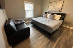a bedroom with a bed and a leather chair at Now and Zen in Charlotte