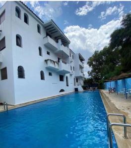 a pool in front of a building with blue water at Coastal Apartment in Cabo in Cabo Negro