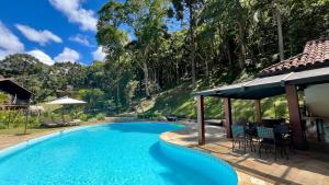 a swimming pool with chairs and a gazebo at Casa 02 Vale Boa Vista - Casa em Condomínio Exclusivo com Vista para as Montanhas e Área de Lazer Completa in Teresópolis