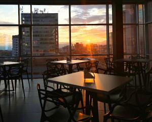 ein Restaurant mit Tischen und Stühlen vor einem Sonnenuntergang in der Unterkunft Giluxe Hotel in Pereira