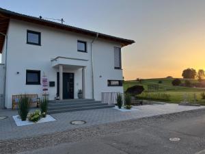 a white house with the sunset in the background at Schönes 1 Zimmer Apartment in Hüfingen
