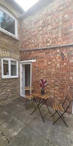 a patio with a table and chairs next to a brick wall at Charming Village Cottage with Parking in Uffington +3 photos