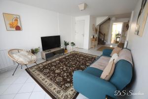 ein Wohnzimmer mit einer blauen Couch und einem Fernseher in der Unterkunft Nest - Maison Rénovée, Parking gratuit, Fibre in Saintes + 4 Fotos