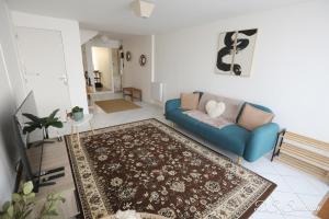 ein Wohnzimmer mit einem blauen Sofa und einem Teppich in der Unterkunft Nest - Maison Rénovée, Parking gratuit, Fibre in Saintes