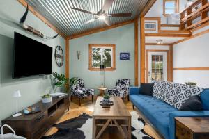 ein Wohnzimmer mit einem blauen Sofa und einem Fernseher in der Unterkunft Hollmig Trio - Sleeps 18 Cowboy Pool & 3 Hot Tubs in Fredericksburg