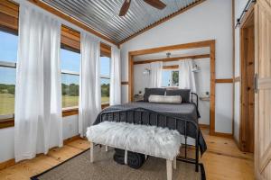 ein Schlafzimmer mit einem Bett in einem Zimmer mit Fenstern in der Unterkunft Hollmig Trio - Sleeps 18 Cowboy Pool & 3 Hot Tubs in Fredericksburg
