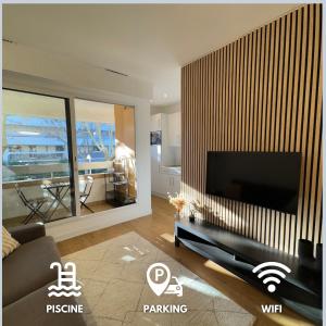 ein Wohnzimmer mit einem großen Flachbildfernseher in der Unterkunft Centre-Ville, 5 min de la Plage, parking, piscine in La Grande-Motte