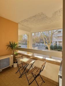 ein Raum mit Tisch und Stühlen und einem großen Fenster in der Unterkunft Centre-Ville, 5 min de la Plage, parking, piscine in La Grande-Motte