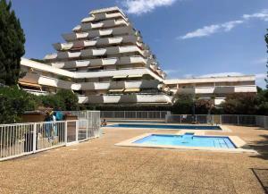 ein Gebäude mit einem Swimmingpool vor einem Gebäude in der Unterkunft Centre-Ville, 5 min de la Plage, parking, piscine in La Grande-Motte