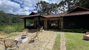 un patio con sillas frente a una casa en Casa 04 Vale Boa Vista - Casa Charmosa com 3 Suítes e Acesso à Área de Lazer Completa de Condomínio, en Teresópolis