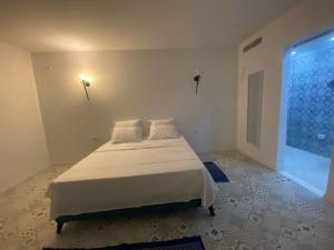 Un dormitorio con una cama blanca y una ventana grande. en Evasion a El hawarea, en El Haouaria 1 foto más