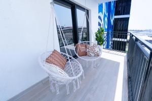 two wicker chairs and pillows on a balcony at 1BR Yas Island - Walk to F1, Ferrari & SeaWorld in Abu Dhabi