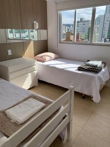a bedroom with two beds and a window at Apartamento fantástico com linda vista lateral do mar in Balneário Camboriú +53 photos
