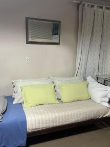 ein Bett mit gelben Kissen und ein Fenster mit einer Klimaanlage in der Unterkunft SUITE FAMILIAR EN CENTRO CIUDAD DE MENDOZA COCHERA DISPONiBLE in Barraquero