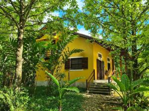 a yellow house with stairs in a forest at Chalés Villa do Mar in Ubatuba