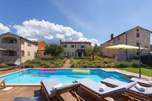 une piscine avec des chaises et une maison dans l'établissement Villa Baldasi, à Vižinada