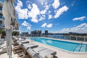 a pool on the roof of a building with lounge chairs and an umbrella at Champagne at Tiffany's - Luxury Condo by the Beach in Fort Lauderdale