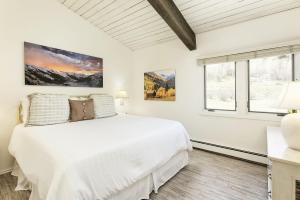 a white bedroom with a bed and two windows at 21E condo in Snowmass Village