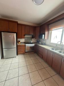 a kitchen with wooden cabinets and a stainless steel refrigerator at Casa de playa, a pasos del mar in Mazatlán