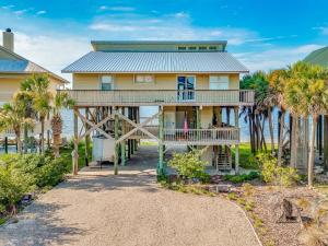 a yellow house with palm trees in front of it at Just Like Heaven - Beachfront in Panacea