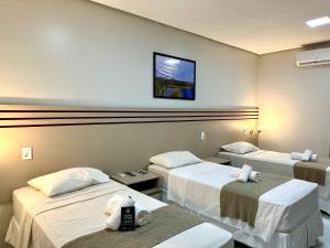 a room with two beds and a tv on the wall at Valen Porto Hotel São Luís in São Luís
