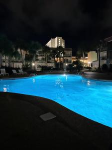 a large blue swimming pool at night at Locally Owned Condo At The Villas in Biloxi