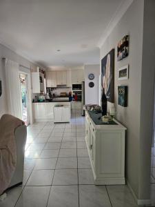 a kitchen with white cabinets and a large tile floor at Gorgeous Private Relaxing Quite Homestay in Westcourt
