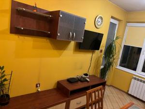 Cette chambre dispose d'une table et d'une télévision sur un mur jaune. dans l'établissement Galina apartment, à Ruse