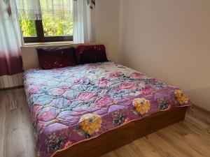 a bed with a purple comforter with flowers on it at HOTEL&Restaurant DALLAS in Myślenice
