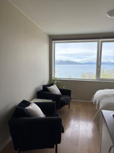 a bedroom with two chairs and a bed and a large window at Cozy Apartment in Tromsø