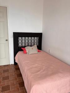 een kleine slaapkamer met een bed met een roze deken bij Hotel la barranca 5 in Zacatlán