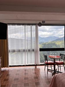 een kamer met een tafel en stoelen en een groot raam bij Hotel la barranca 5 in Zacatlán