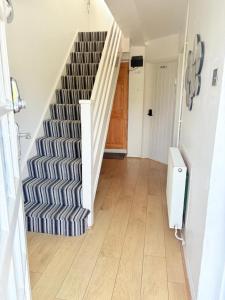 a hallway with a staircase with a blue and white rug at Beaconsfield House - Pleasant Area, Free Parking & Quiet Stay near LTN in Luton